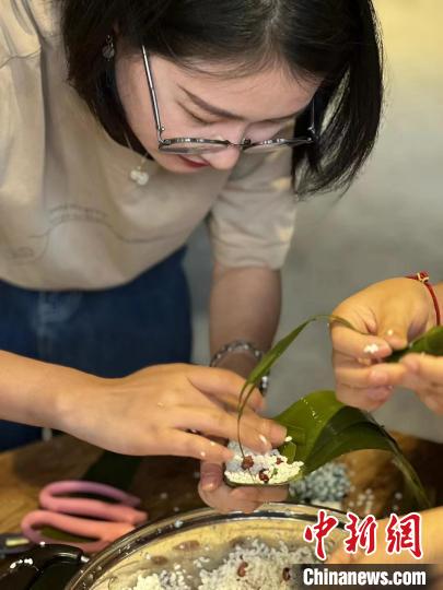 游客在无锡阳山生态旅游区体验包粽子活动