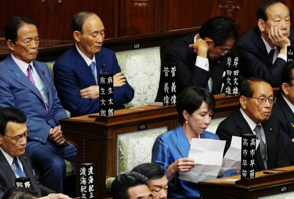 自民党总裁高市早苗（前排右二）在临时国会众议院首相指名选举现场阅读文件 ...